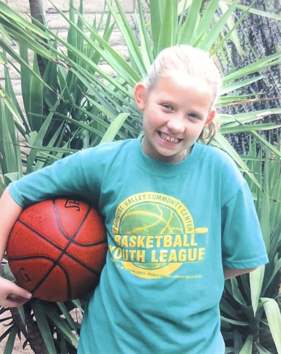 Danielle Bryant as a child, holding a basketball in a Paradise Valley Community Center Basketball Youth League shirt